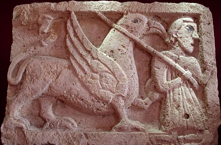 Stone bas-relief of a winged griffin held by a human figure in a tunic, preserved in Palazzo Eroli.