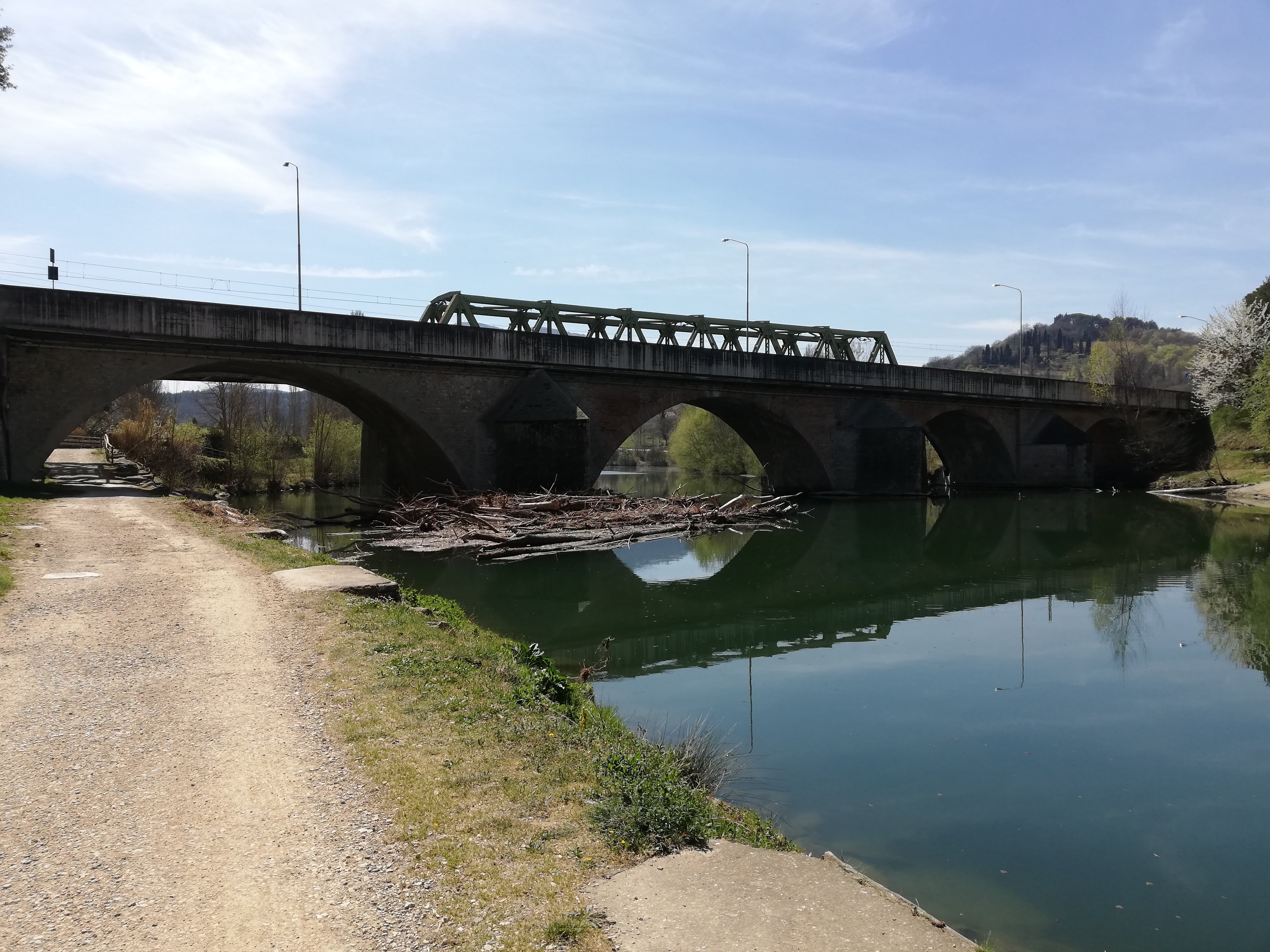 Riverbank with a cycling path and railway bridger
